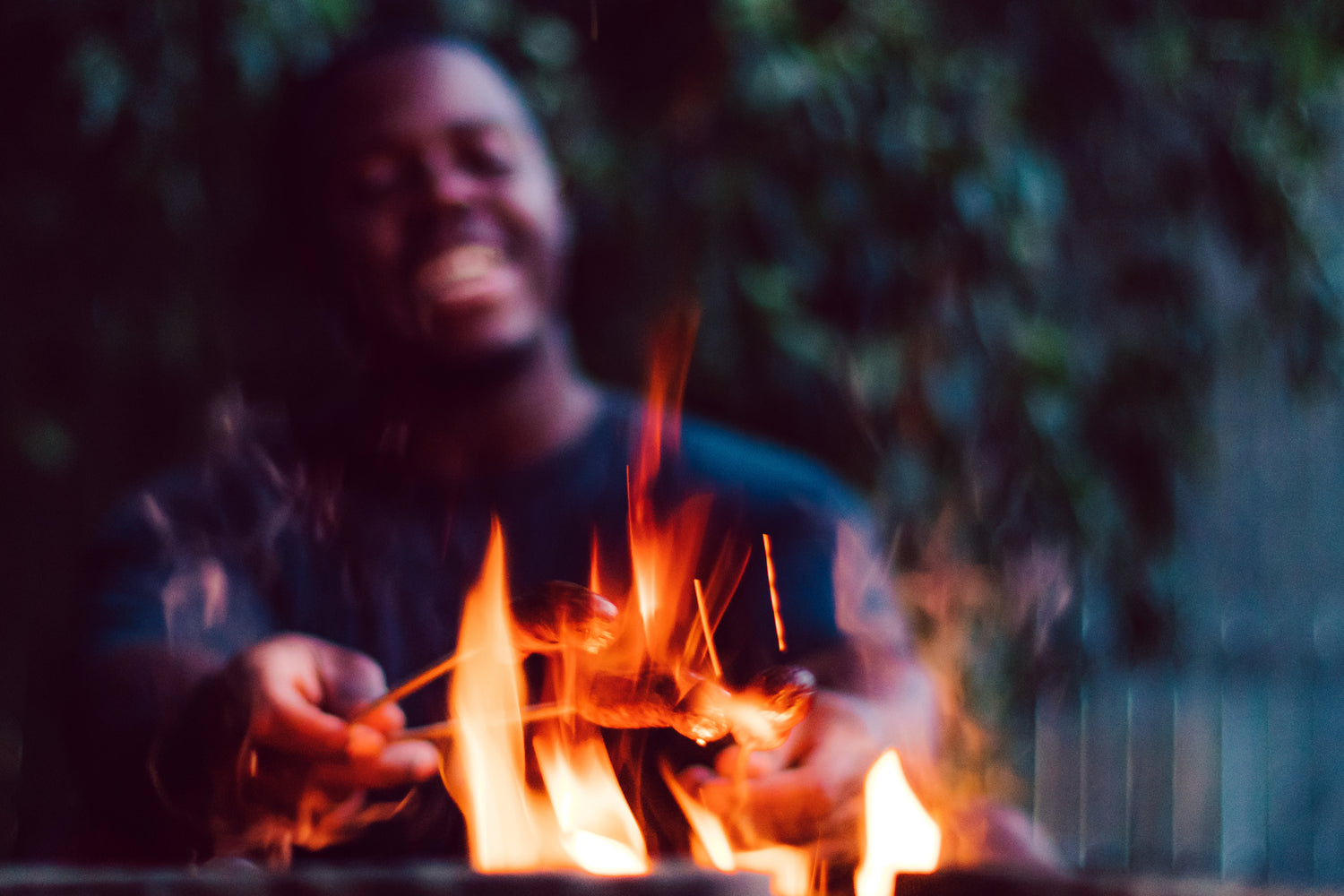 BBQ Stove young black man roasting hotdogs over fire pit